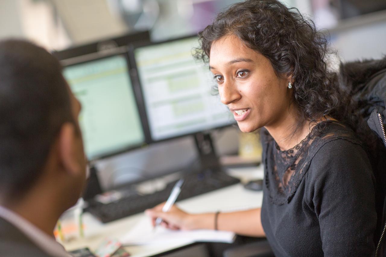 Colleagues talking at desks