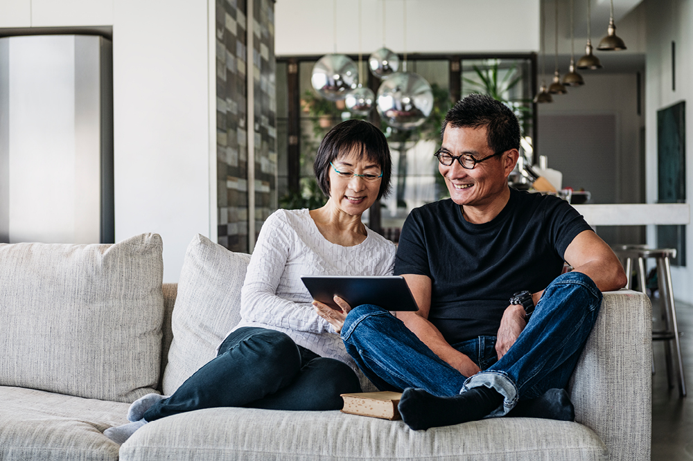Couple sat on sofa looking at tablet
